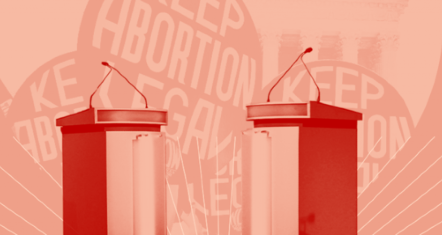 Two debate podiums are placed in front of a pink background with protest signs reading Keep Abortion Legal
